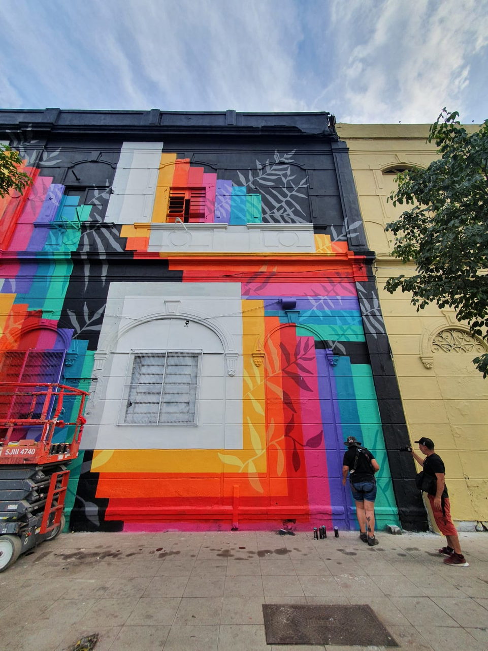 Regenbogenfassade in Untersicht mit zwei Malern