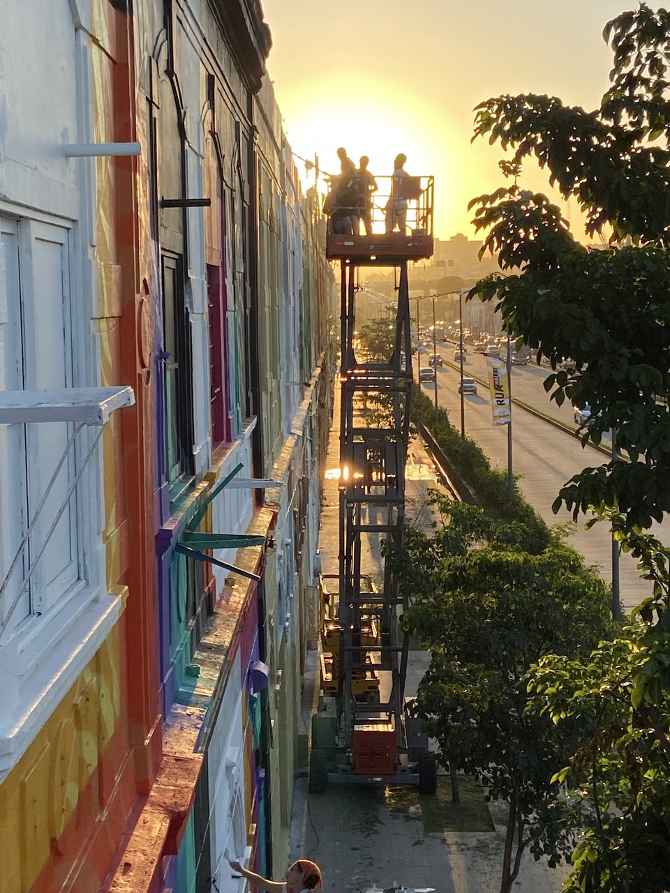 Fassade in Arbeit bei Sonnenuntergang, Team auf den Hubbühnen