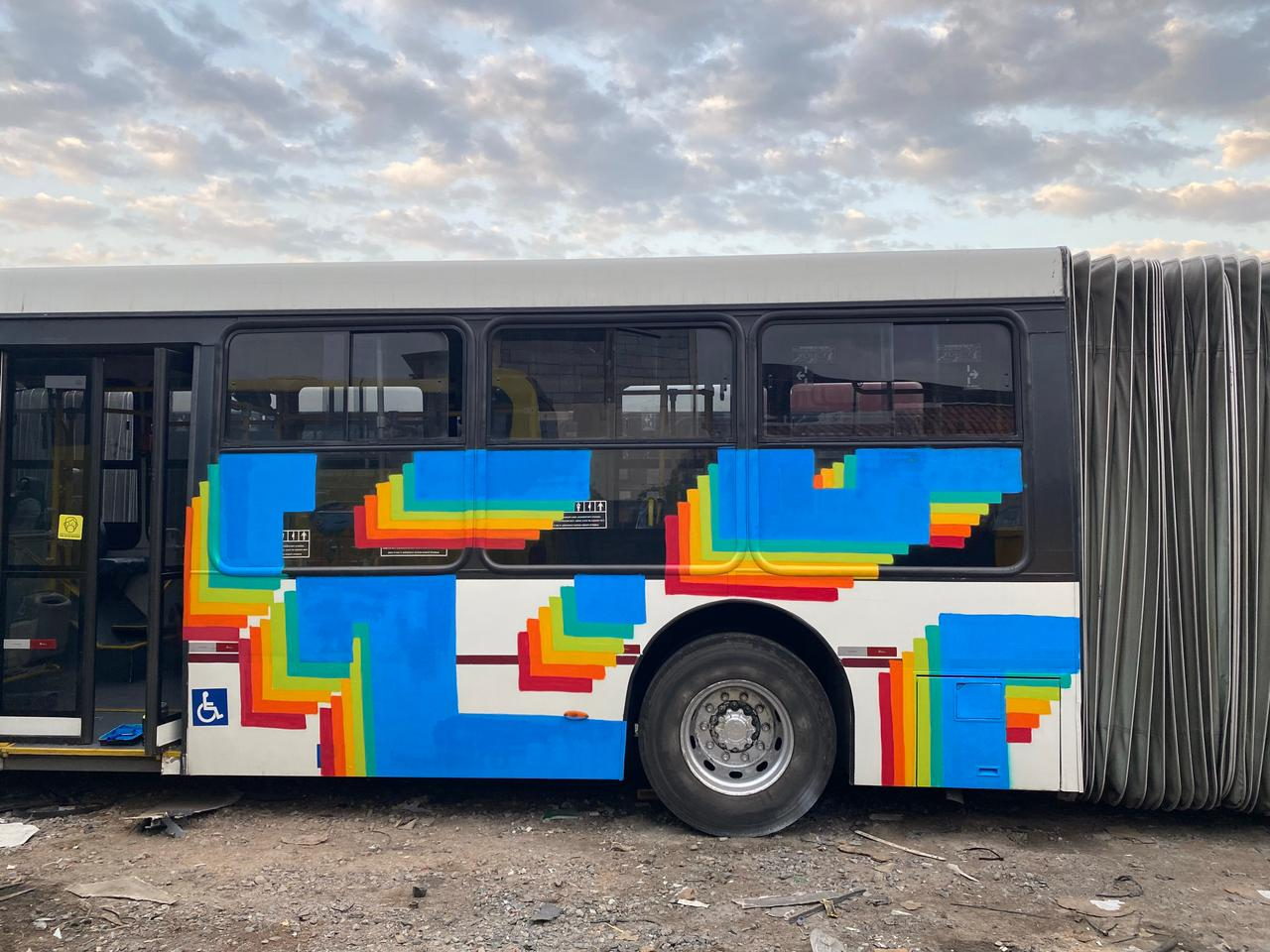 Ônibus pintado com padrão escalonado em azul e arco-íris