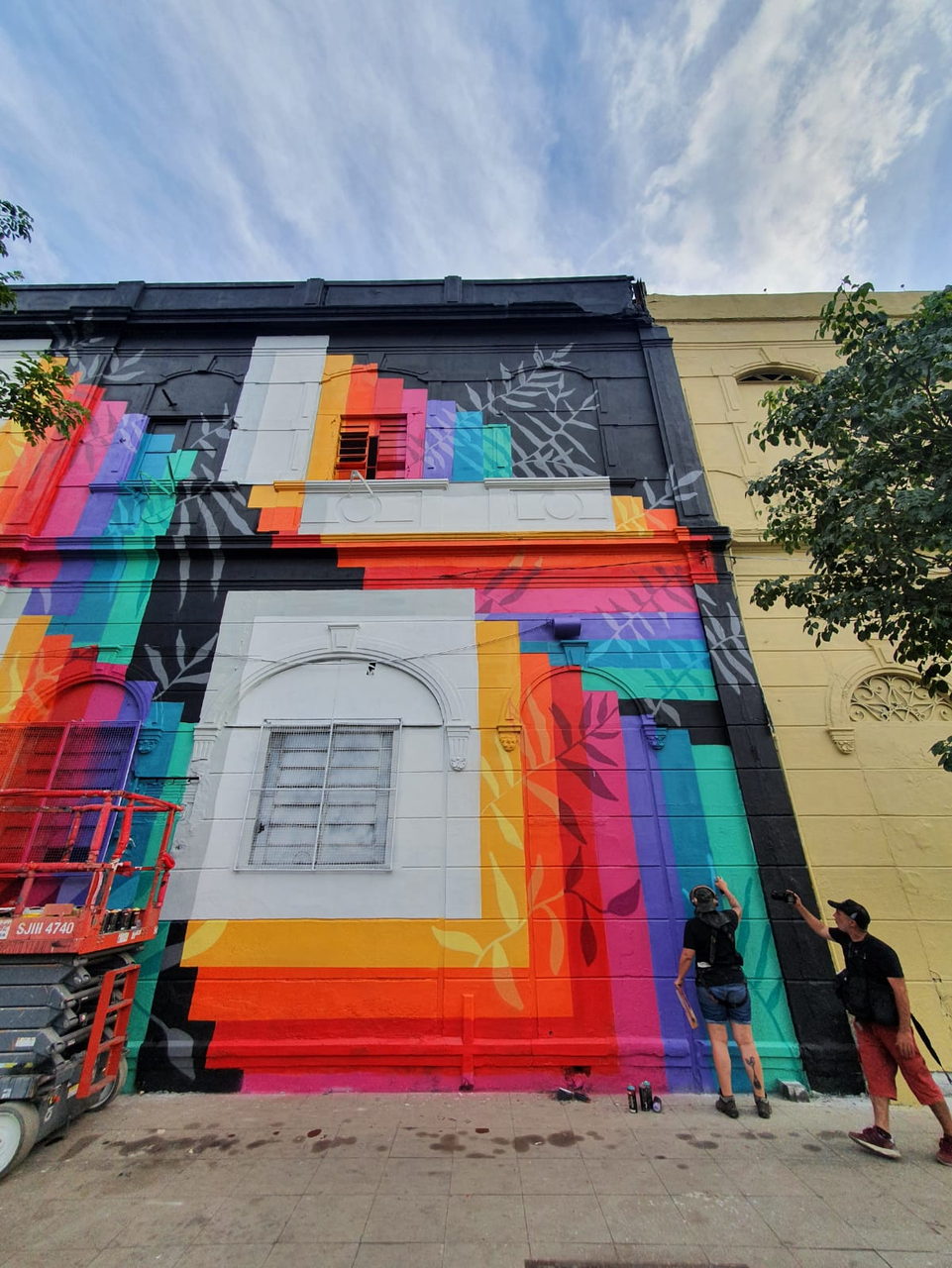 Regenbogenfassade in Untersicht mit zwei Malern