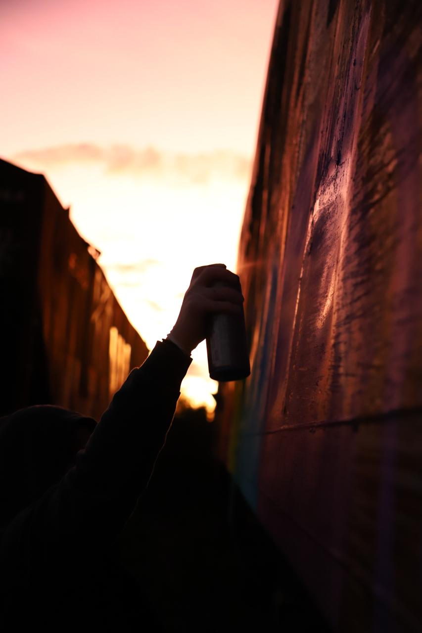 Mão pintando um vagão contra o pôr do sol